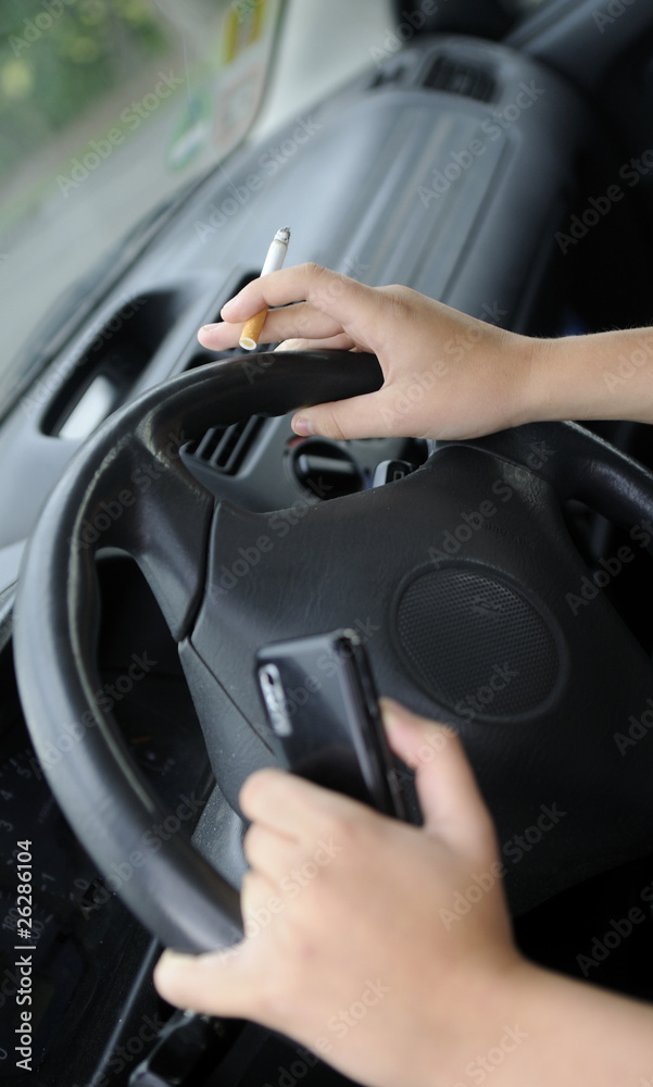 Zigarette und Handy am Autolenkrad