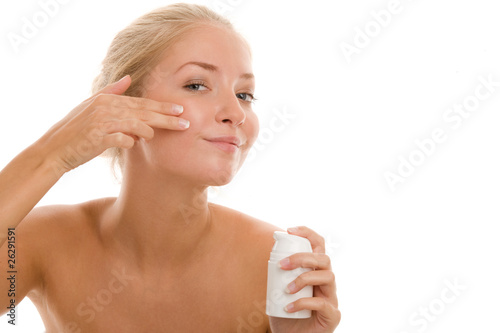 Woman applying cream on cheek photo