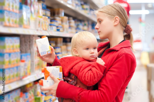 Young mother with baby daughter shopping in supermarket