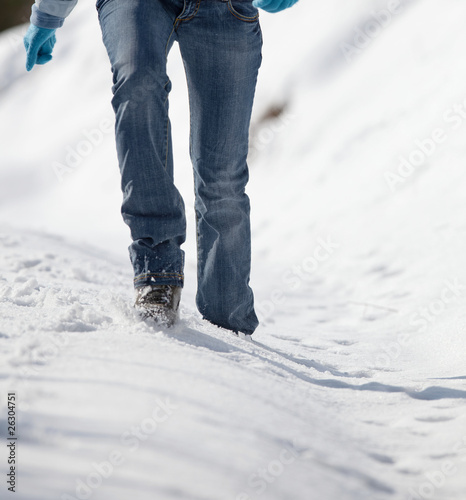 pretty young woman walking in deep snow on a sunny winter day