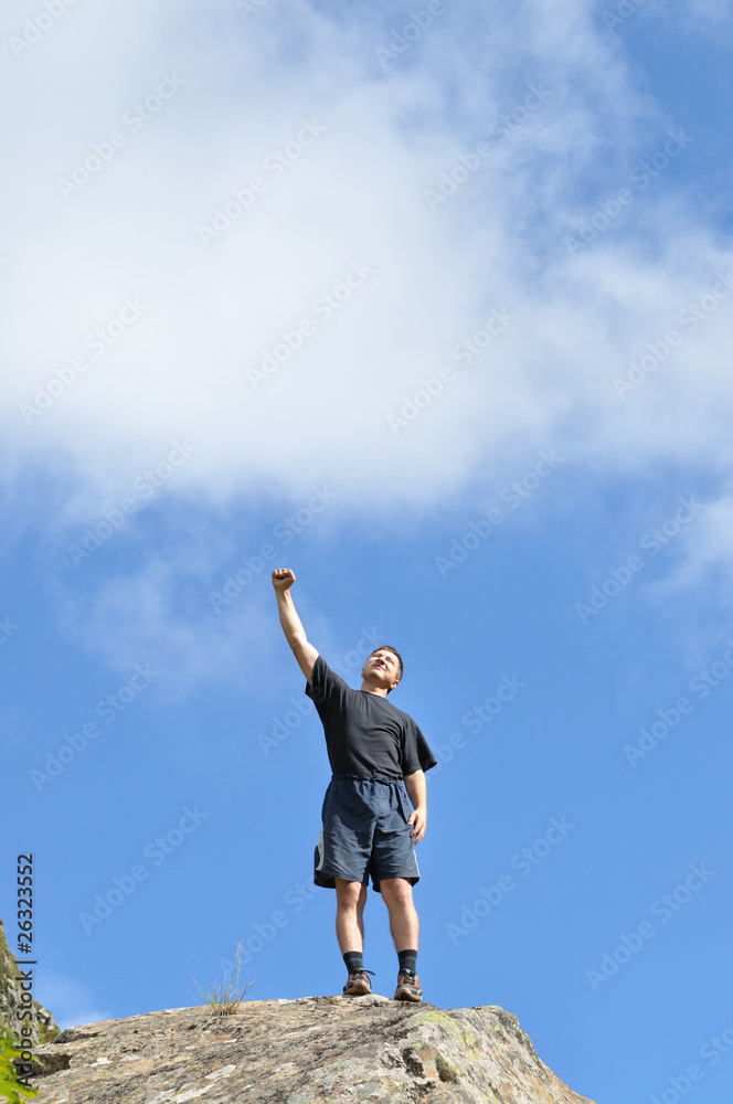 A young man stands on a cliff top and raised his hands A young man stands on a cliff top and raised his hands