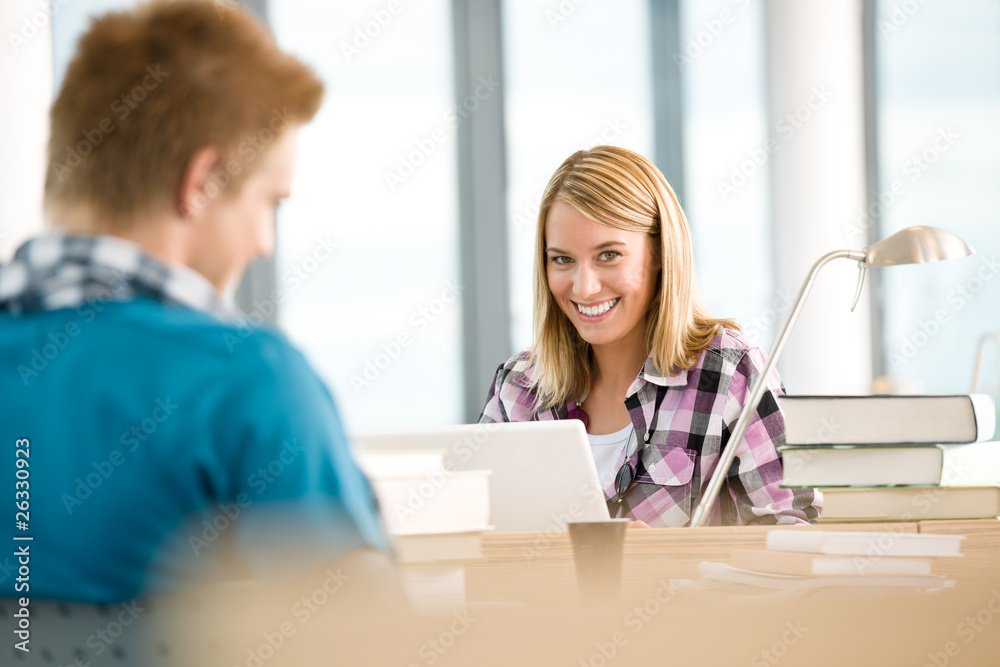 Two students with books and laptop