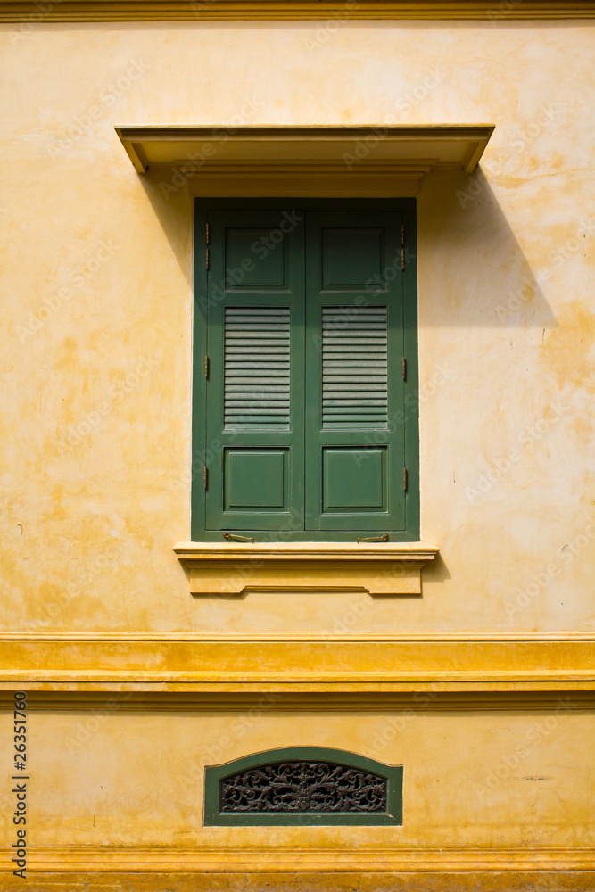 green window shutters on yellow wall with great shadows