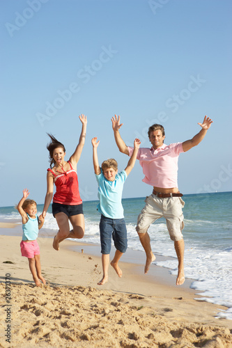 Portrait Of Family On Beach Holiday Jumping In Air