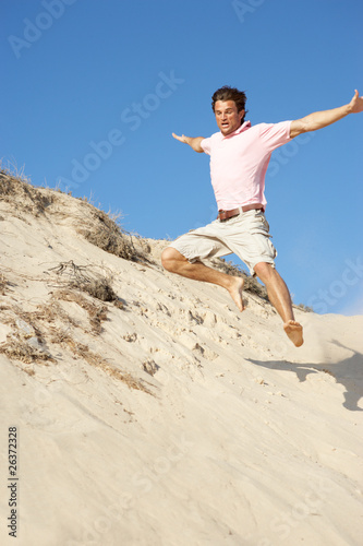 Young Man Enjoying Beach Holiday Running Down Dune