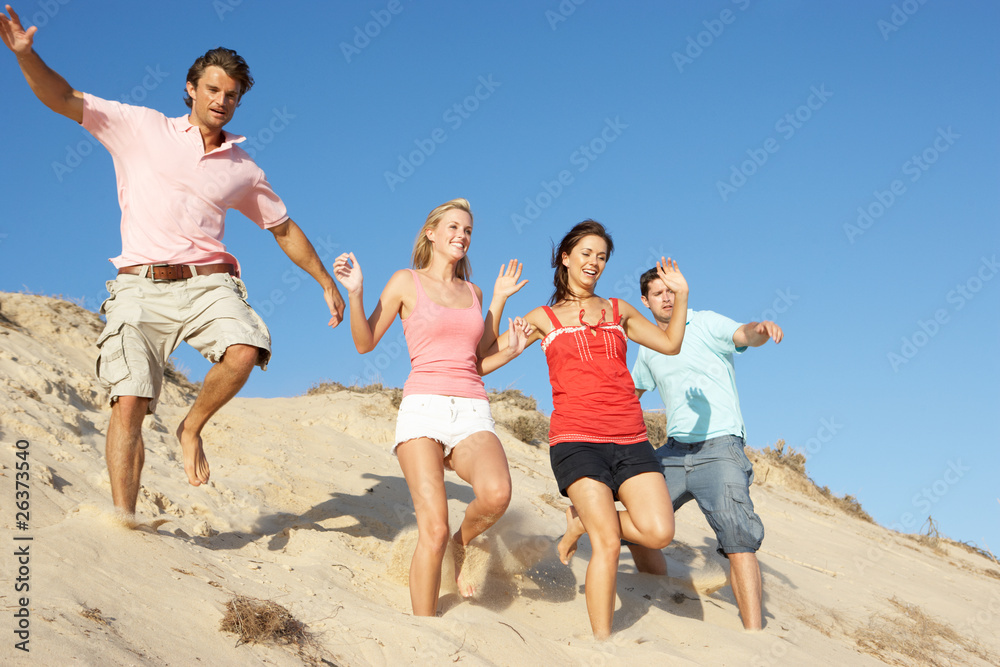 Group Of Friends Enjoying Beach Holiday Running Down Dunes Group Of Friends Enjoying Beach Holiday Running Down Dunes