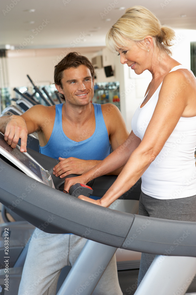 Senior Woman Working With Personal Trainer On Running Machine In Senior Woman Working With Personal Trainer On Running Machine In