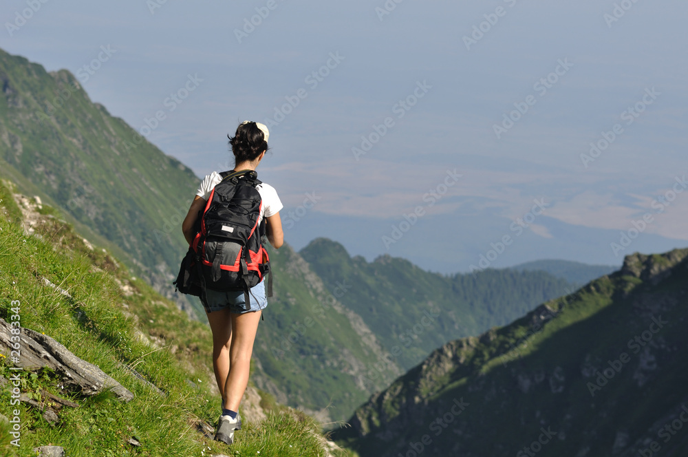 single woman with backpack walking on mountains