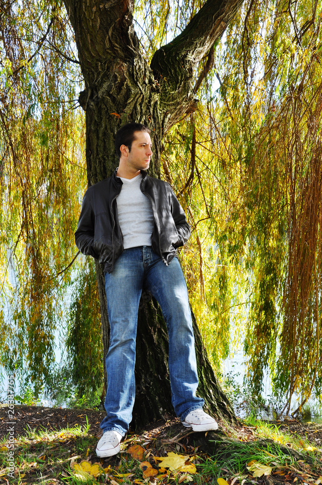 Young man leaning against a willow tree