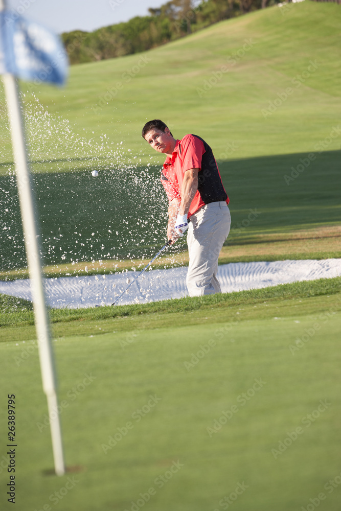 Male Golfer Playing Bunker Shot On Golf Course