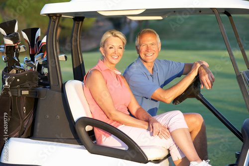 Senior Couple Riding In Golf Buggy On Golf Course