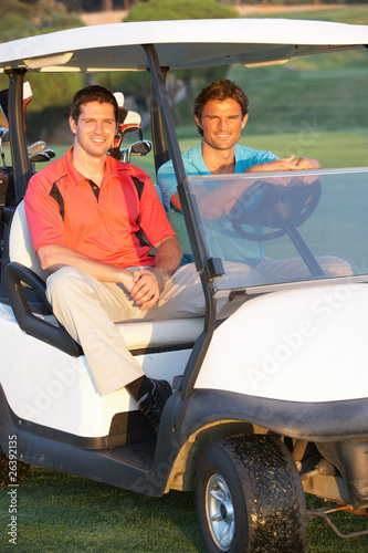 Two Male Golfers Riding In Golf Buggy On Golf Course