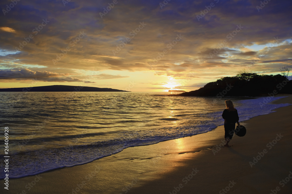 woman walking on the shore at makena, maui at sunset