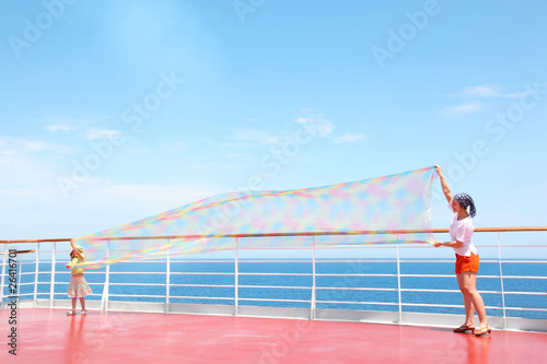 mom and daughter unfolded enormous scarf on deck of yacht