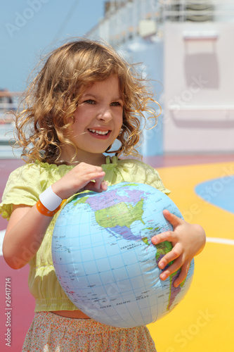 little girl standing on cruise liner deck and holding globe