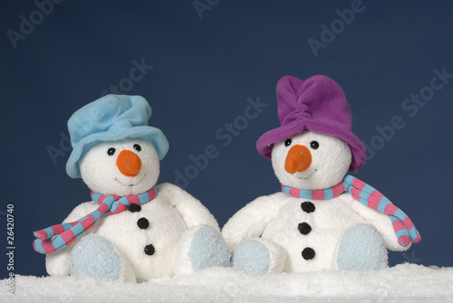 two cute snowmen sitting in the snow
