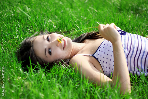 a charming young woman lying on a summer meadow
