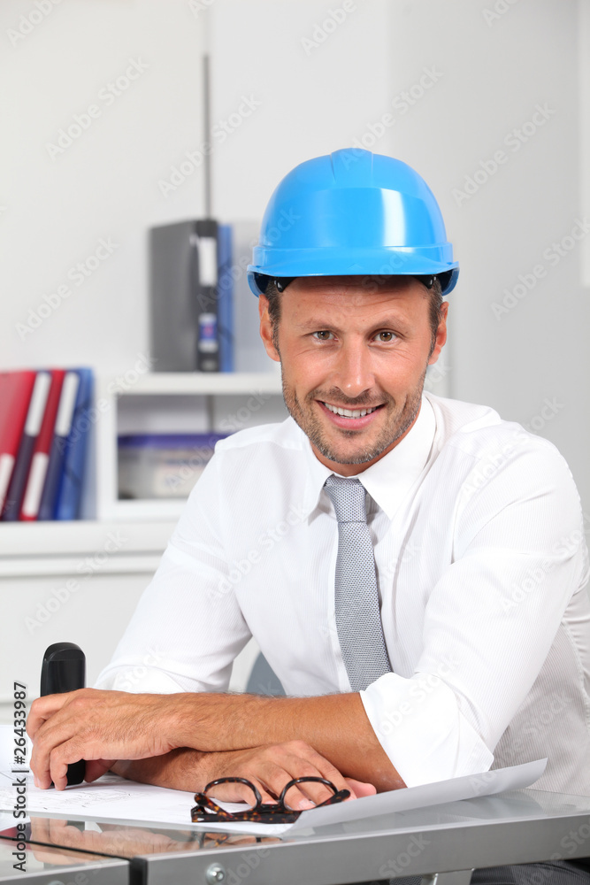 Site manager in the office with blue helmet Site manager in the office with blue helmet