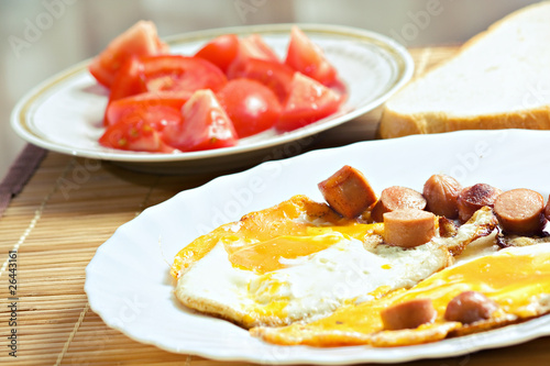 Breakfast with eggs, sausage, bread and tomato