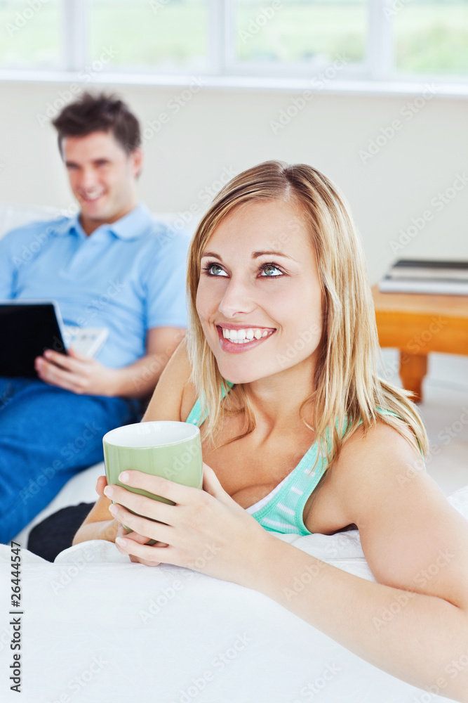 young couple. woman drinking tea when man using a laptop young couple. woman drinking tea when man using a laptop