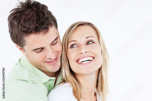handsome man hugging his laughing girlfriend against a white bac