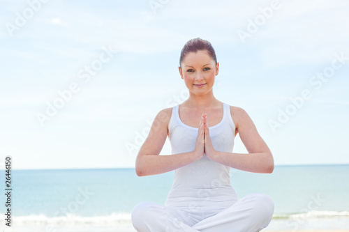 Caucasan woman practicing yoga on the beach