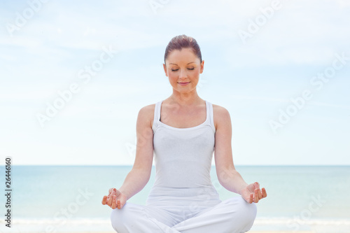 Caucasian healthy woman doing yoga on beach