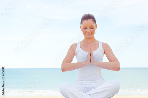 Concentrated woman practicing yoga on the beach