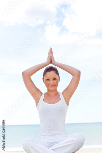 Young concentrated woman doing yoga on beach