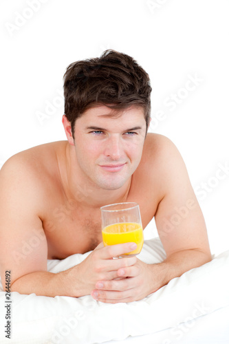 pretty man lying on his bed with a glass of orange juice