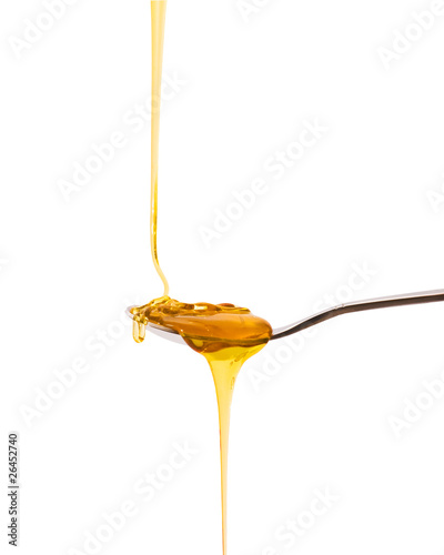 Honey on a spoon over a white background