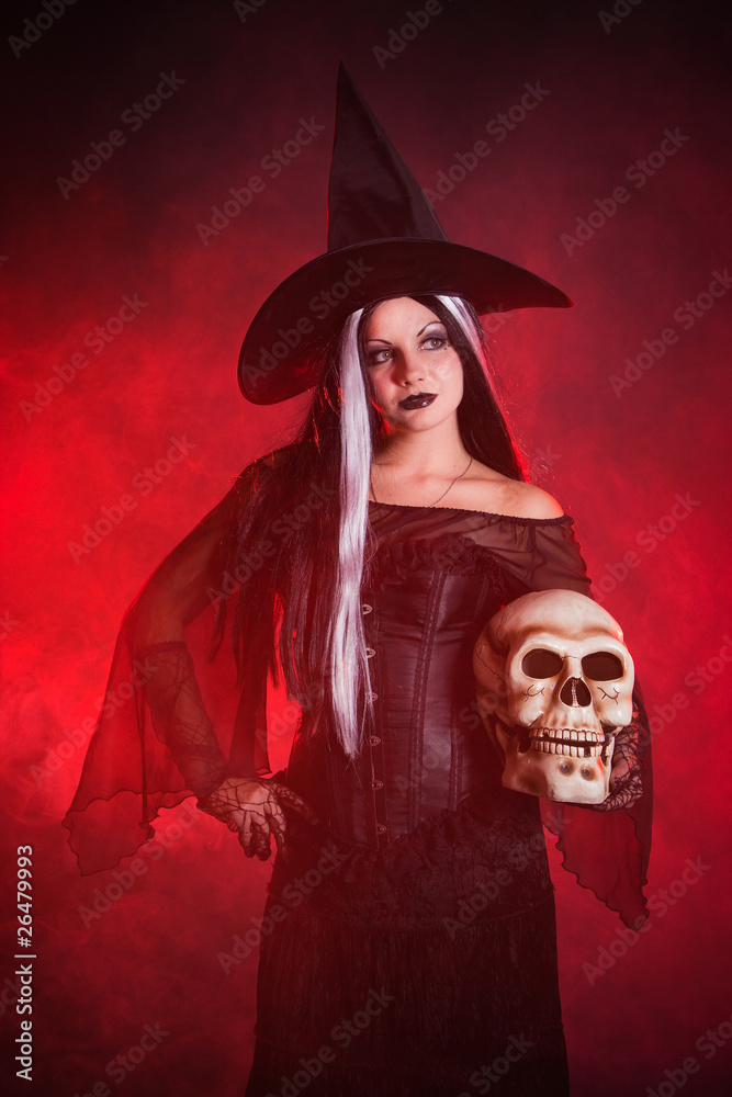 Halloween witch with a skull over color background with smoke