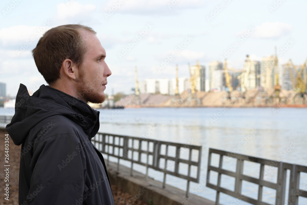 portrait of young man standing on river embankment and looking i portrait of young man standing on river embankment and looking i