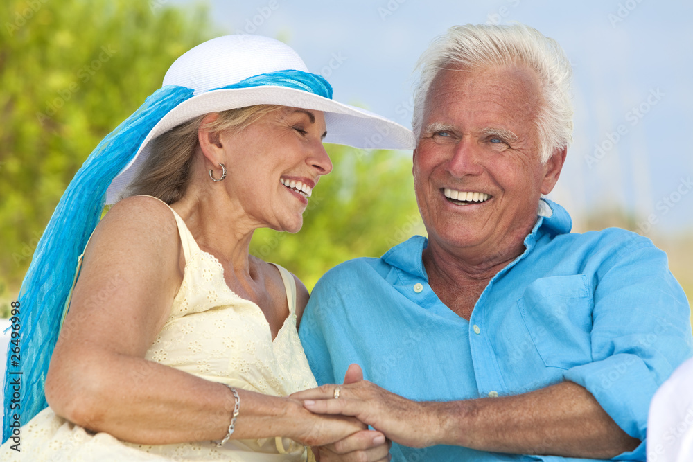 Happy Senior Couple Holding Hands & Laughing at the Beach Happy Senior Couple Holding Hands & Laughing at the Beach