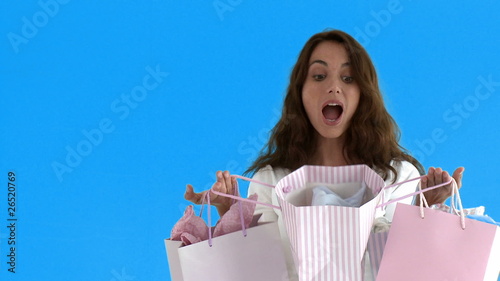 Suprised woman opening shopping bags standing on blue screen photo