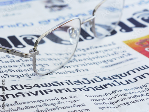 Close-up of Thai language newspaper and a pair of glasses