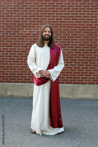 Man in Jesus robe and sash next to brick wall