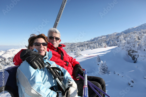 Homme et femme seniors assis sur un télésiège à la neige