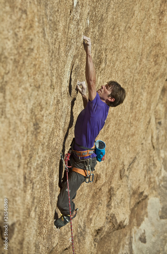 Rock climber clinging to steep cliff.