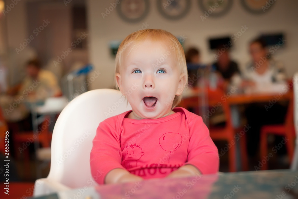 Adorable toddler girl sitting on chair in cafe near mother Adorable toddler girl sitting on chair in cafe near mother