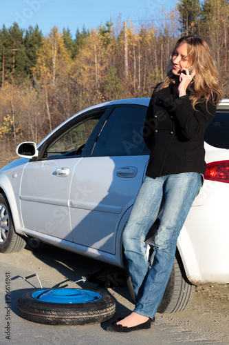 Young woman standing by her damaged car and calling for help © Nobilior