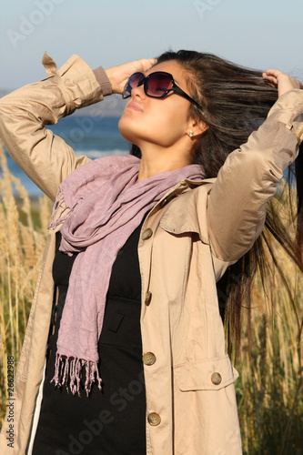 girl in beige autumn coat correcting her hair