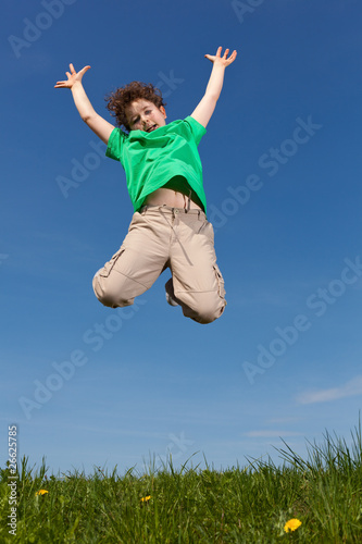 Boy jumping, running against blue sky