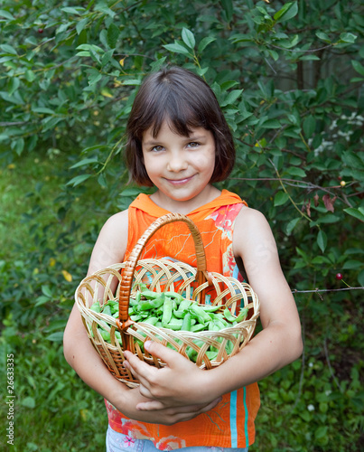 The girl in an orange vest with peas basket