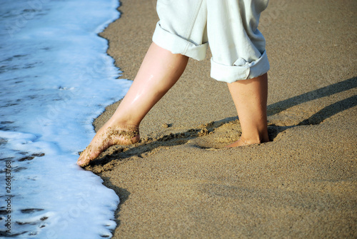 female feet on sand and in sea foam