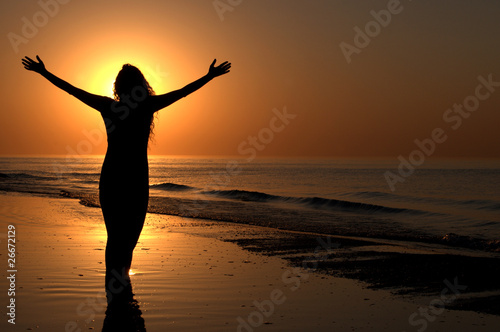 Young adult female with arms wide open on a sunset