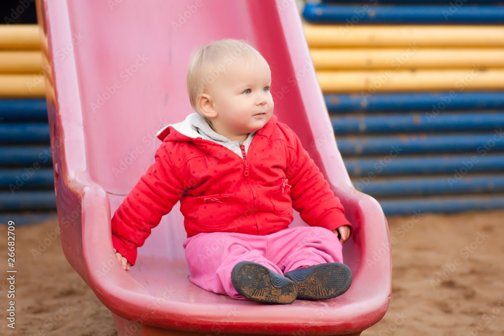 Cute toddler girl sit on side after slide down from top of slide Cute toddler girl sit on side after slide down from top of slide