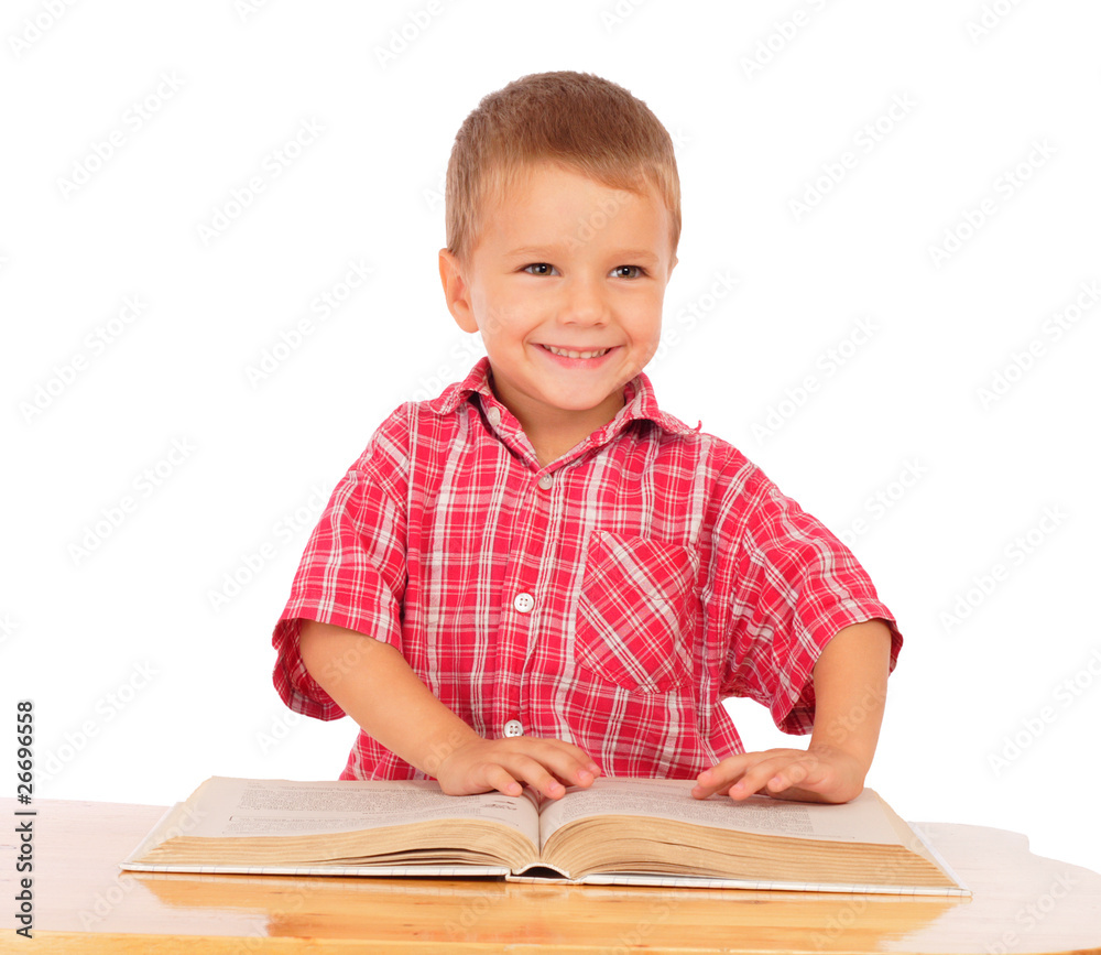 Smiling little boy reading book on the desk, isolated on white Smiling little boy reading book on the desk, isolated on white