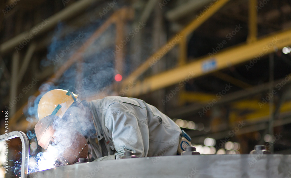 Heavy industry manual worker welding/grinding in a factory - obrazy, fototapety, plakaty 