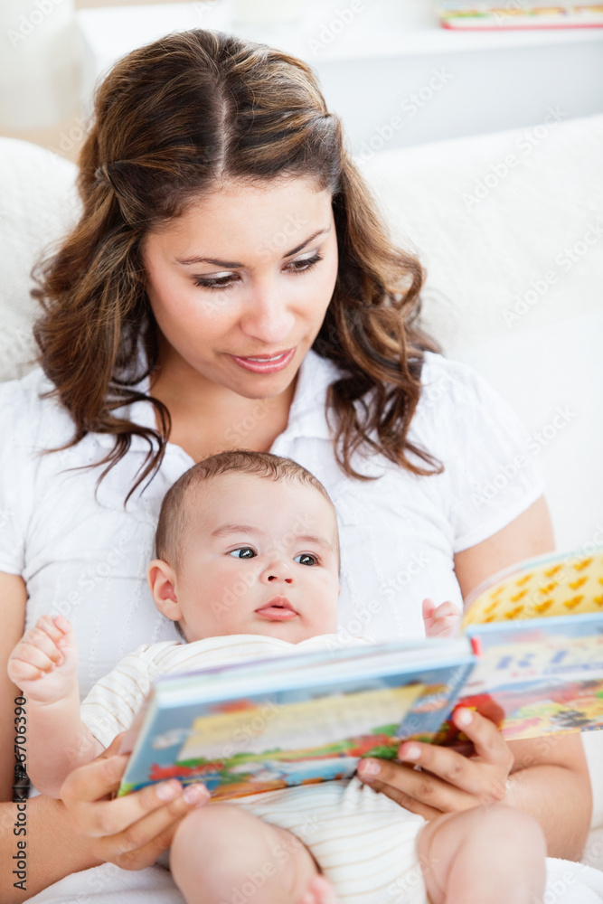 Attentive mother reading a book to her adorable baby Attentive mother reading a book to her adorable baby